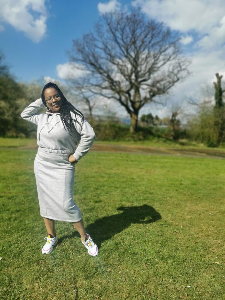 DIY Loungewear. A black woman stands outside wearing a cropped grey hoodie and a grey midi length skirt